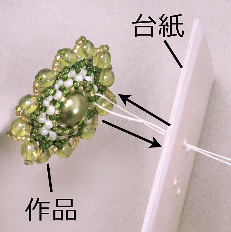 作品を台紙に糸で固定する